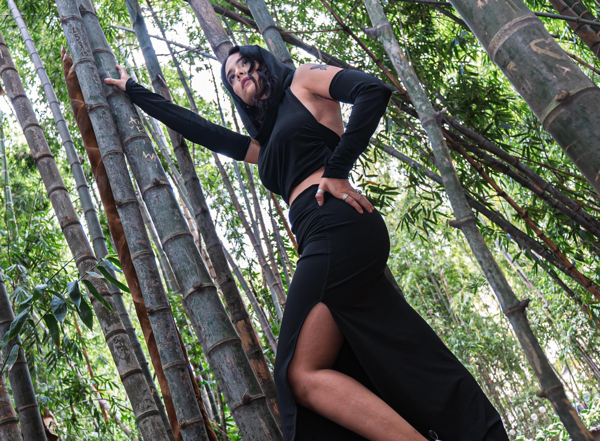 Fashion Fusion campaign — black hooded top and high-slit maxi skirt in a bamboo forest